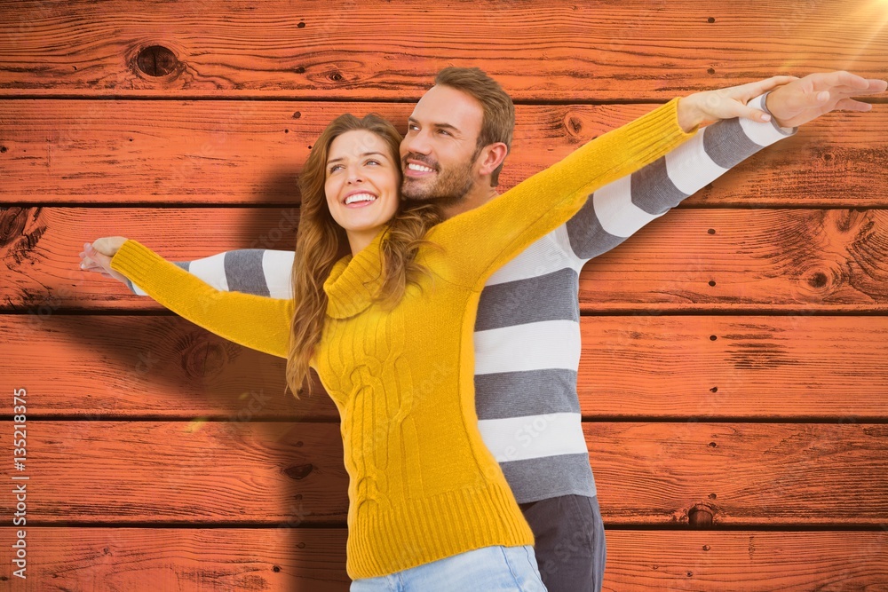 Composite image of young couple standing with arms outstretched