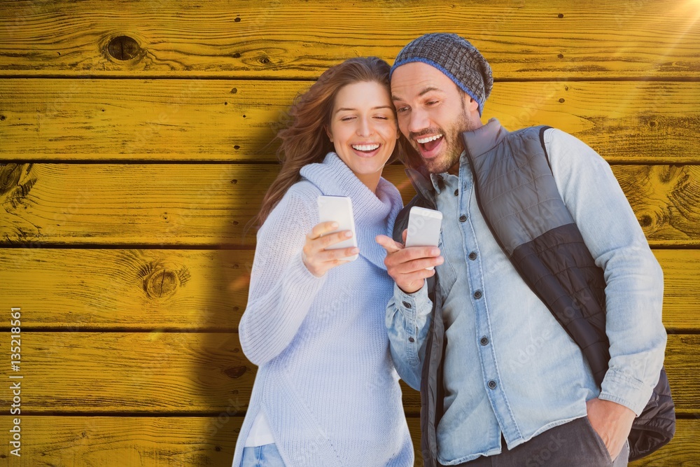 Composite image of happy young couple using mobile phone