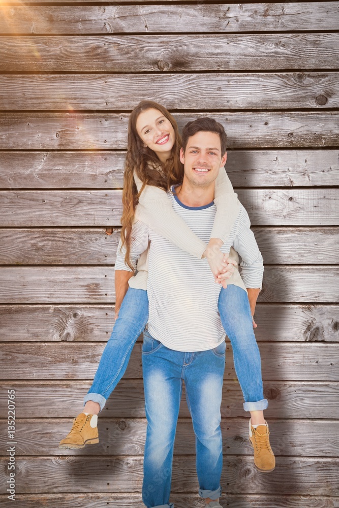 Composite image of portrait of happy young couple piggybacking