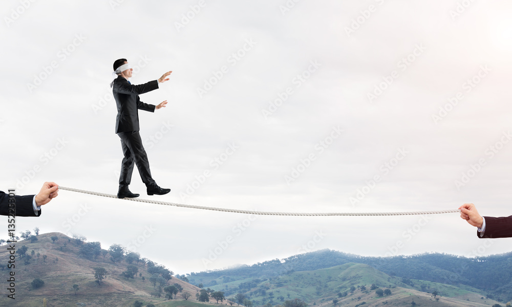 Business concept of risk support and assistance with man balancing on rope