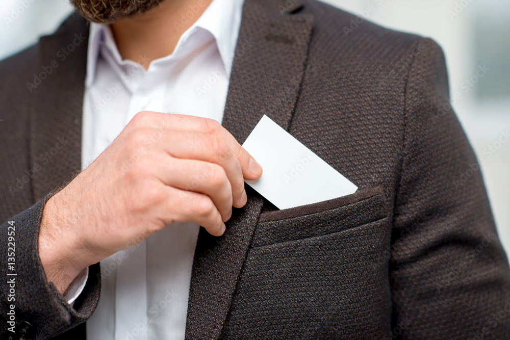 Elegant man in the suit putting business card into the pocket. White card to copy paste