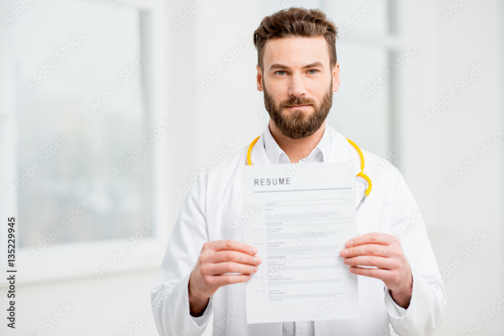 Doctor in uniform holding resume for job hiring in the white interior