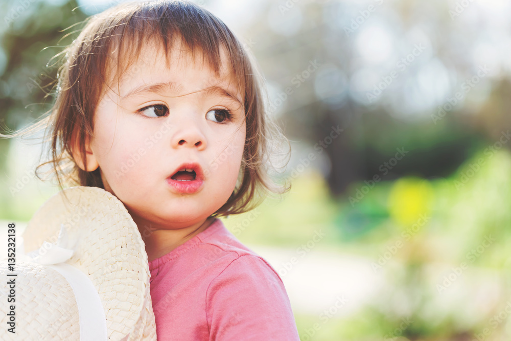 Little girl playing outside in a hat