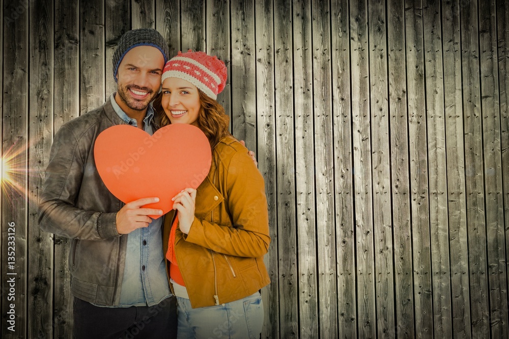 Composite image of young couple holding heart shape paper