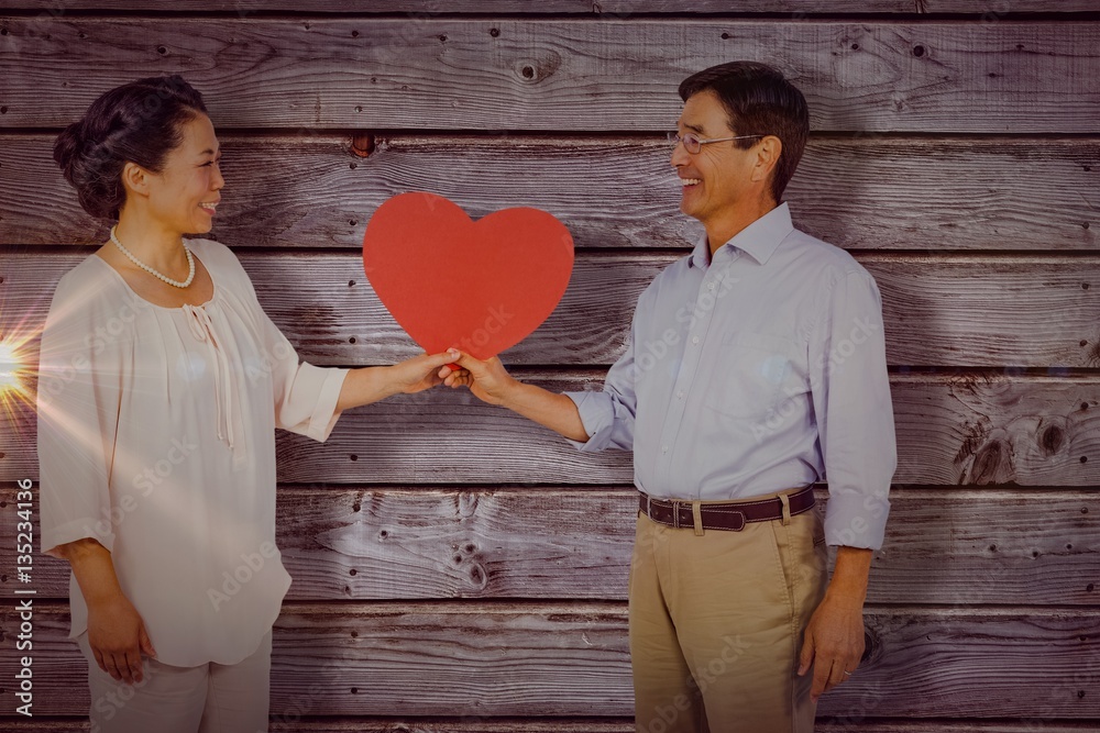 Composite image of older asian couple holding heart