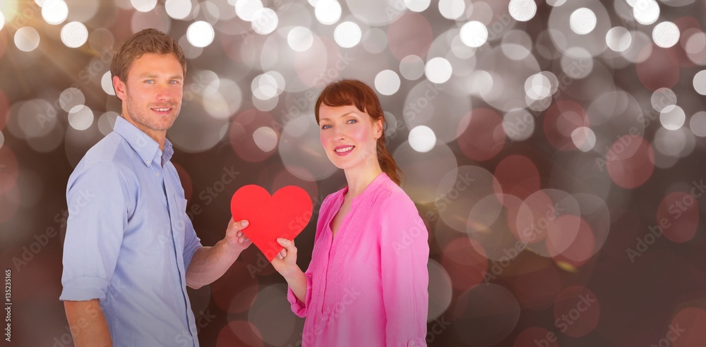 Composite image of couple holding a red heart