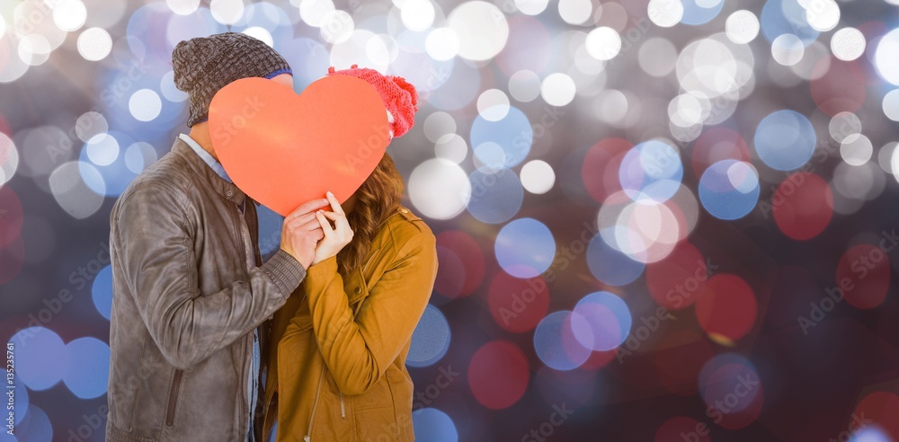 Composite image of happy young couple holding heart shape paper