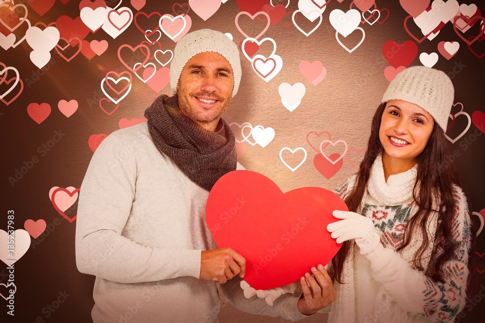 Composite image of smiling couple holding paper heart