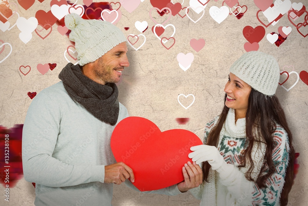 Composite image of smiling couple holding paper heart