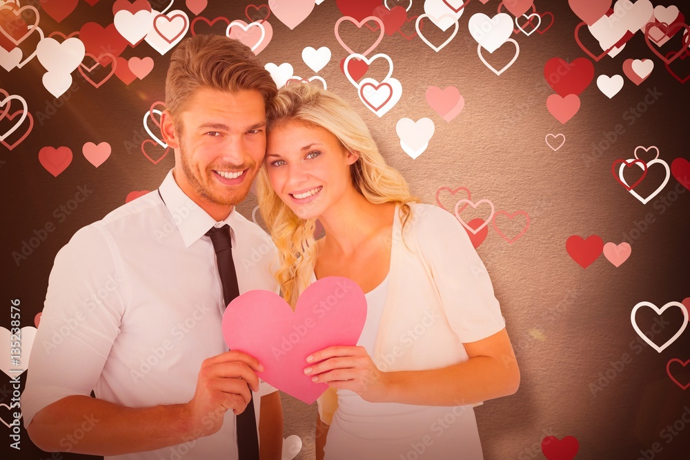 Composite image of attractive young couple holding pink heart