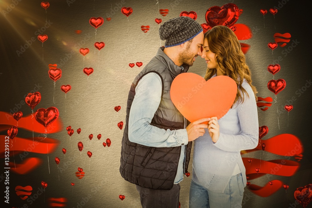 Composite image of happy young couple holding heart shape paper