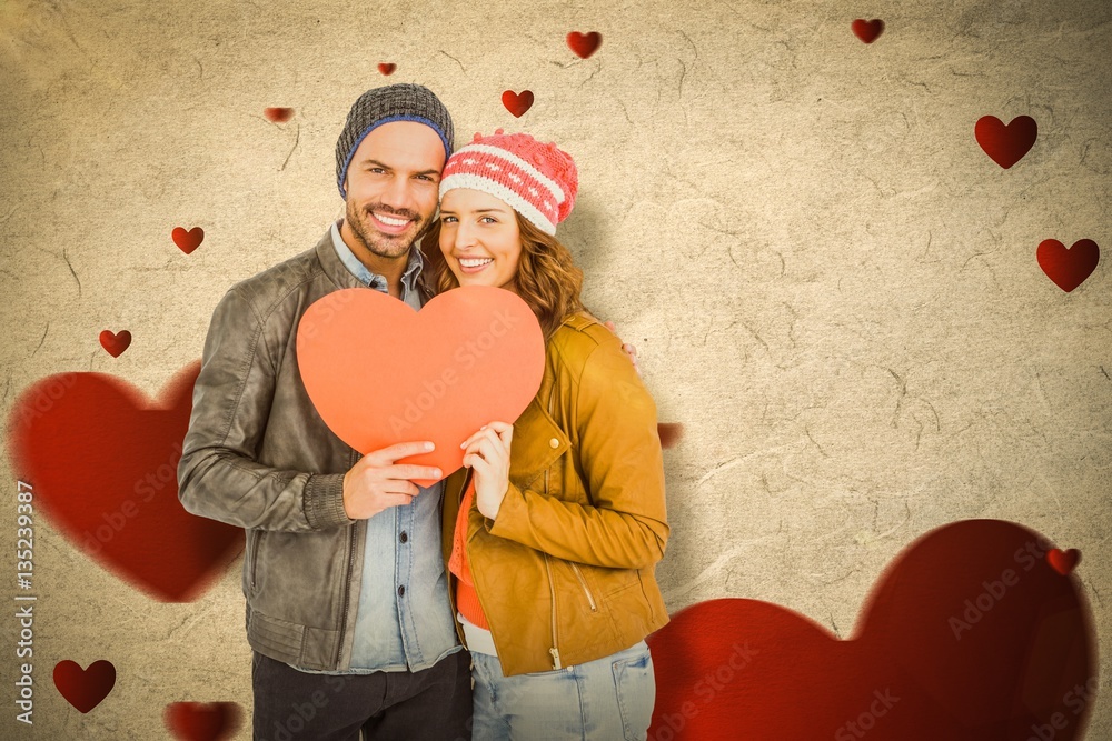 Composite image of young couple holding heart shape paper