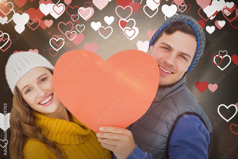 Composite image of happy couple holding heart shape paper