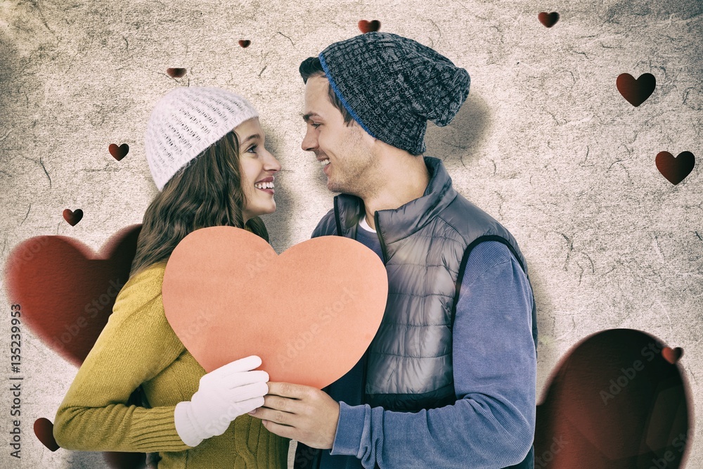 Composite image of happy couple holding paper heart