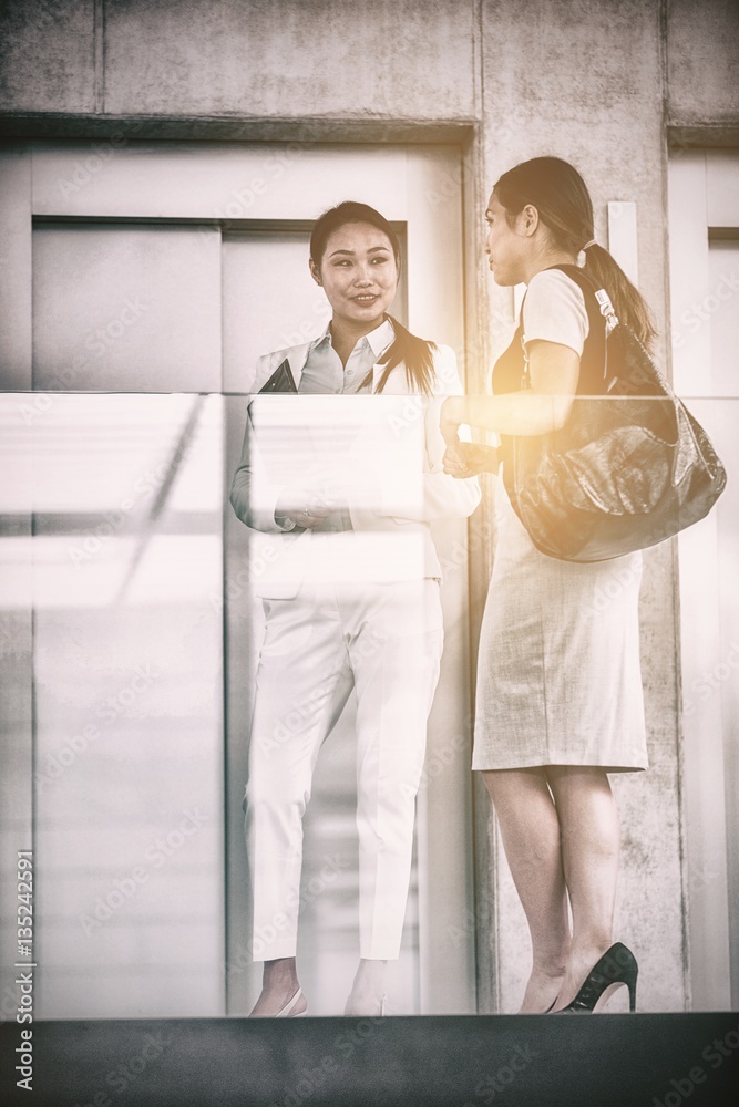 Businesswomen standing by elevator and having conversation