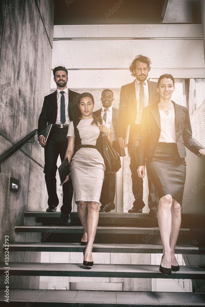 Confident businesswoman with colleagues climbing stairs