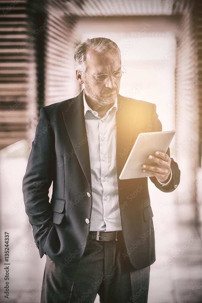 Serious businessman holding digital tablet