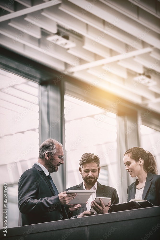 Businesspeople discussing over digital tablet