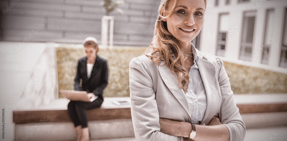 Businesswoman standing with arms crossed in office premises