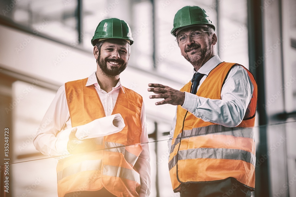 Architects standing with blueprint in office corridor