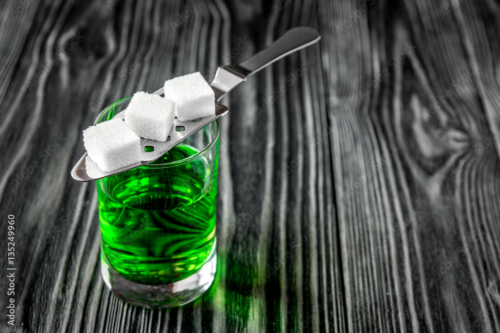 absinthe with sugar cubes and spoon on wooden background