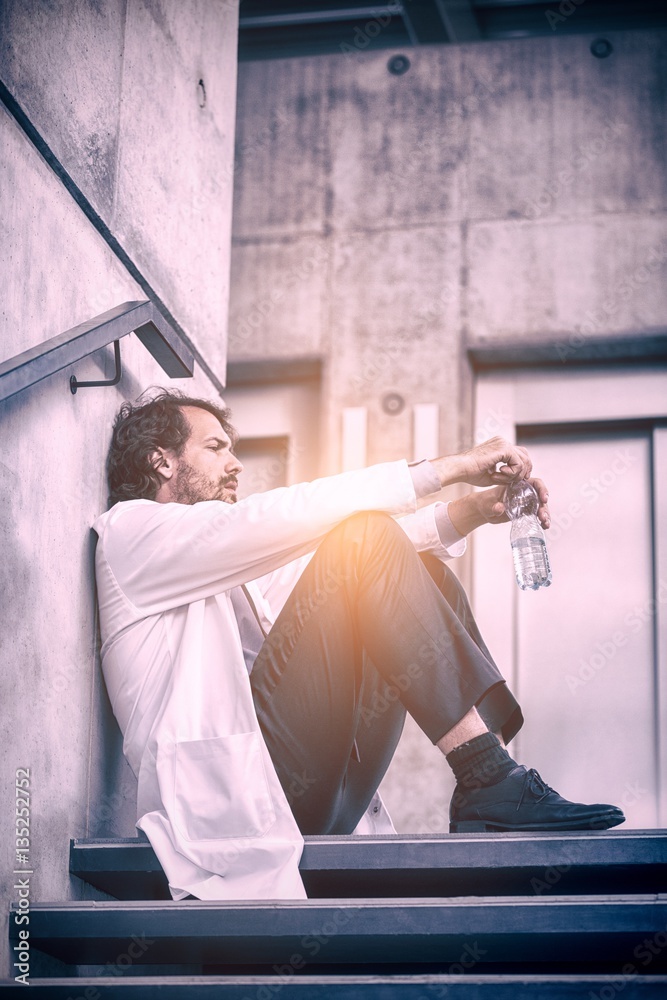 Worried doctor sitting on stairs