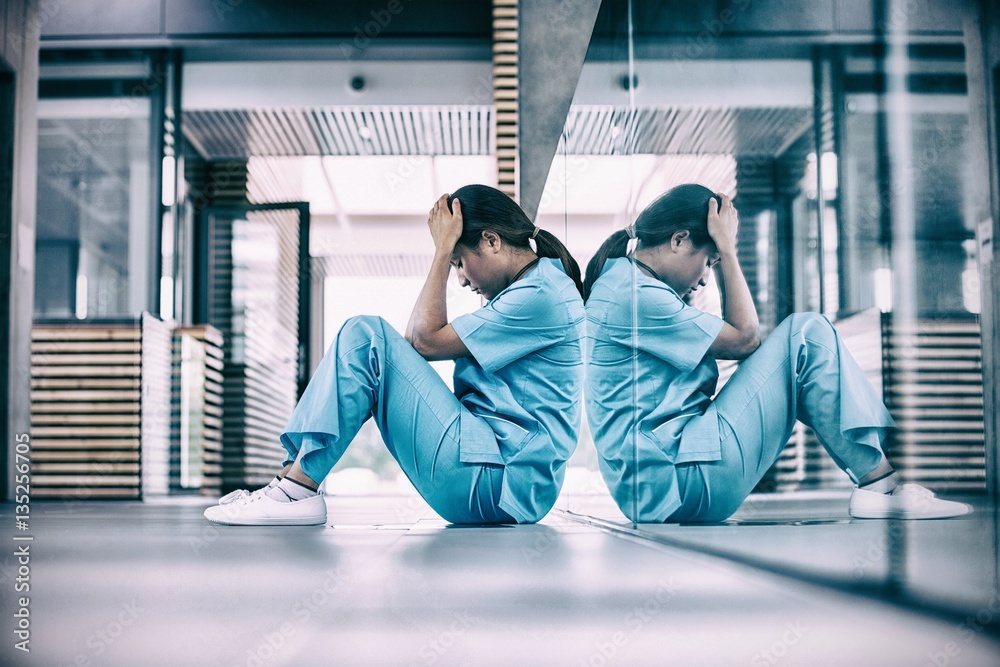 Stressed nurse sitting on floor