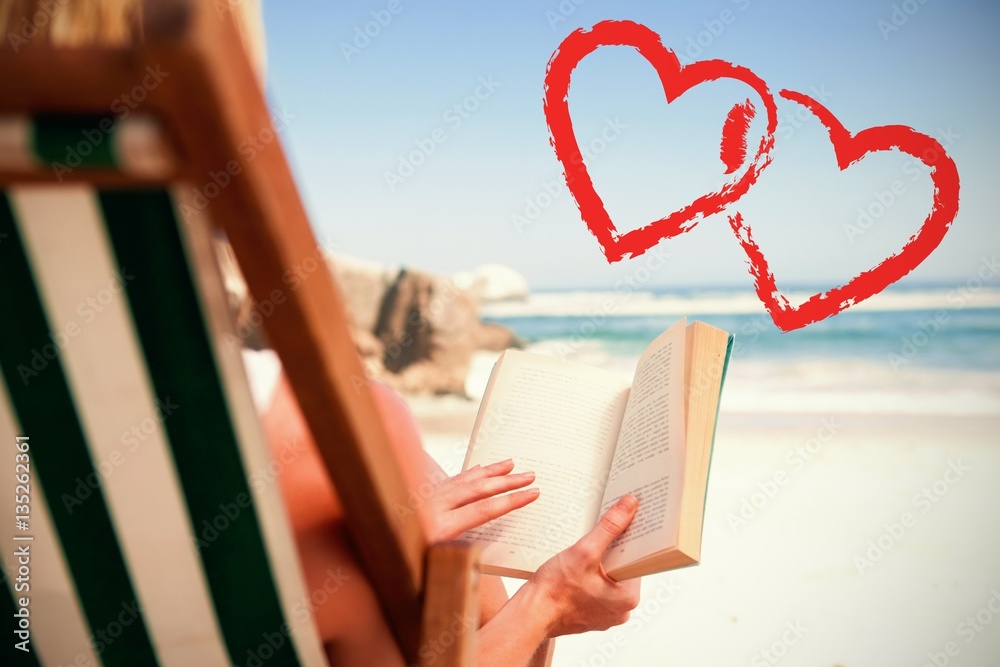 woman sitting in deck chair at beach reading