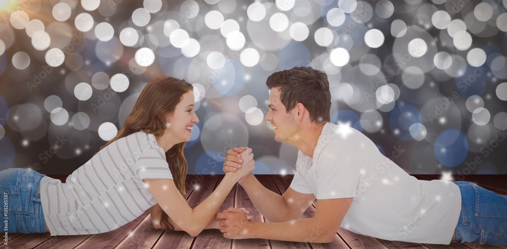 Composite image of happy couple arm wrestling 