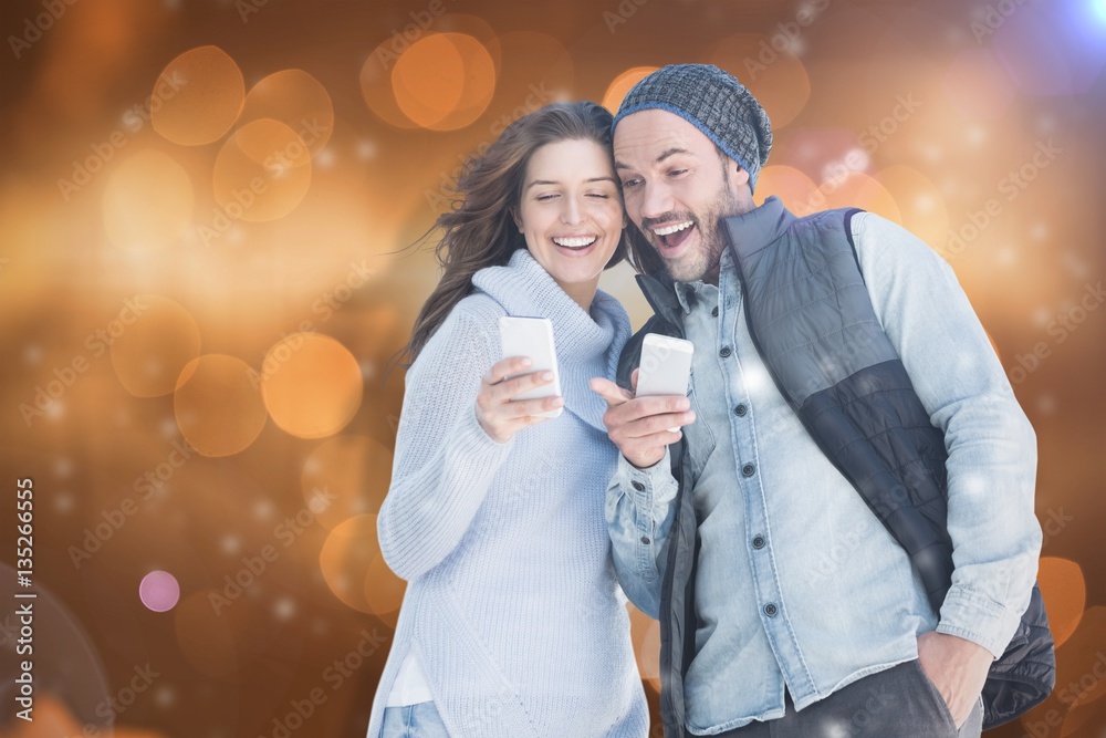 Composite image of happy young couple using mobile phone