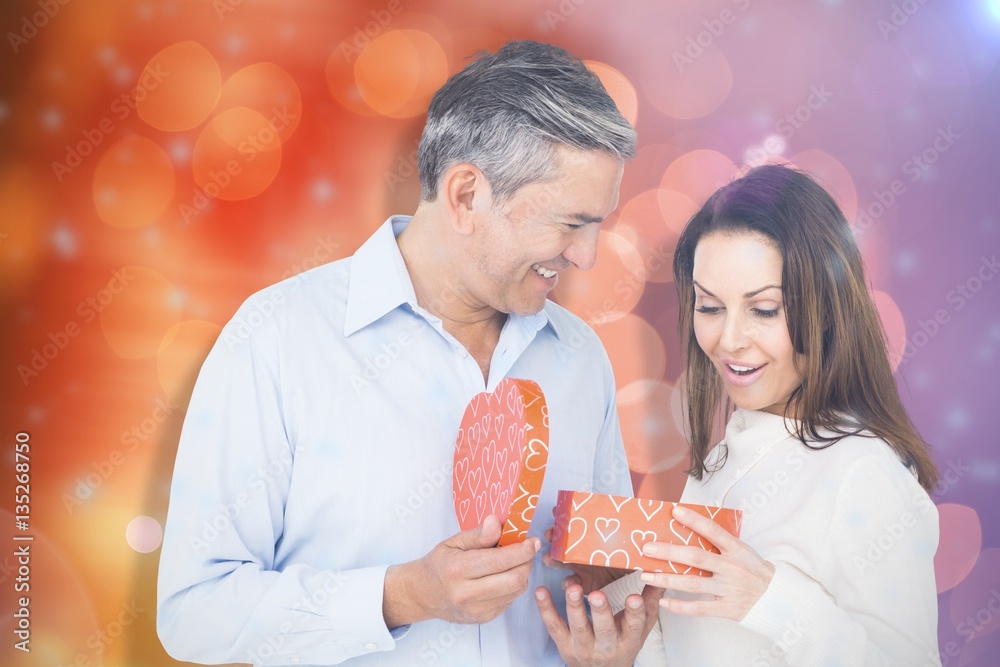 Composite image of happy couple opening present