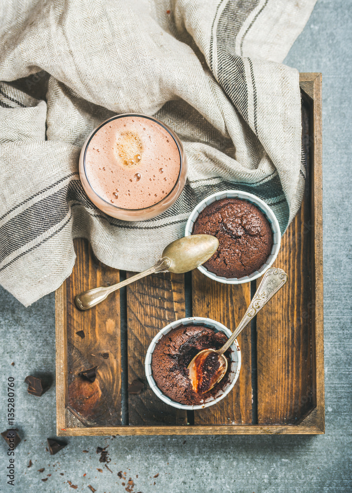 Chocolate souffle in individual baking cups and chocolate mocha coffee in wooden serving tray over g