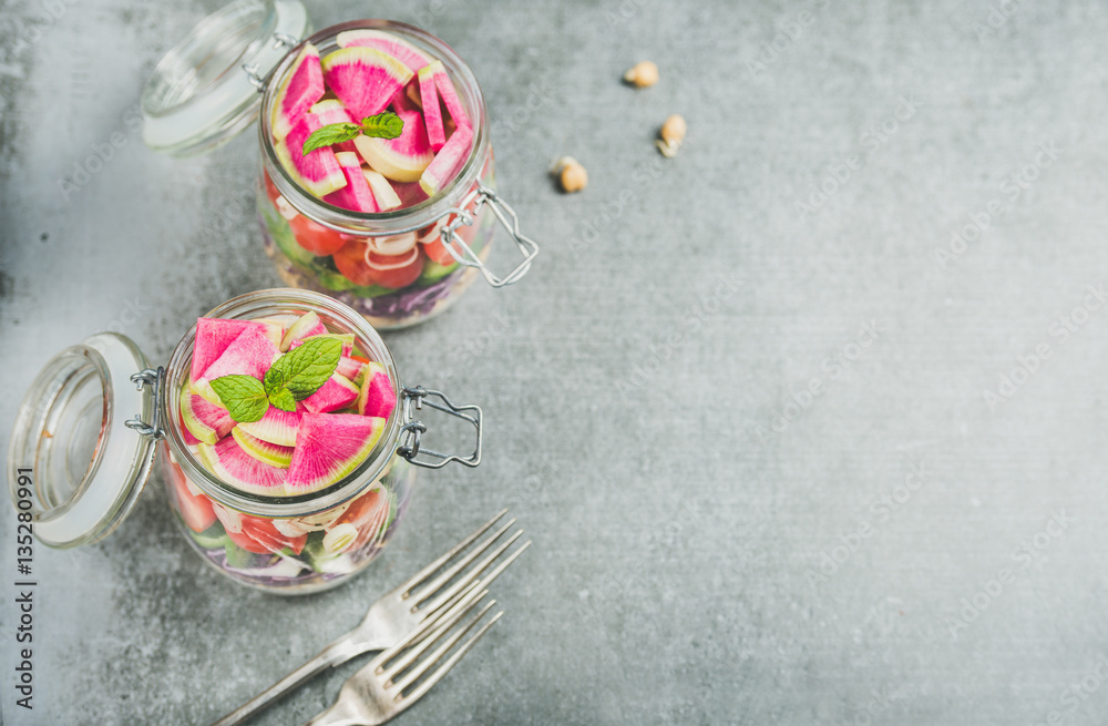 Healthy take-away lunch jars. Vegetable and chickpea sprout vegan salad in glass jars, grey concrete