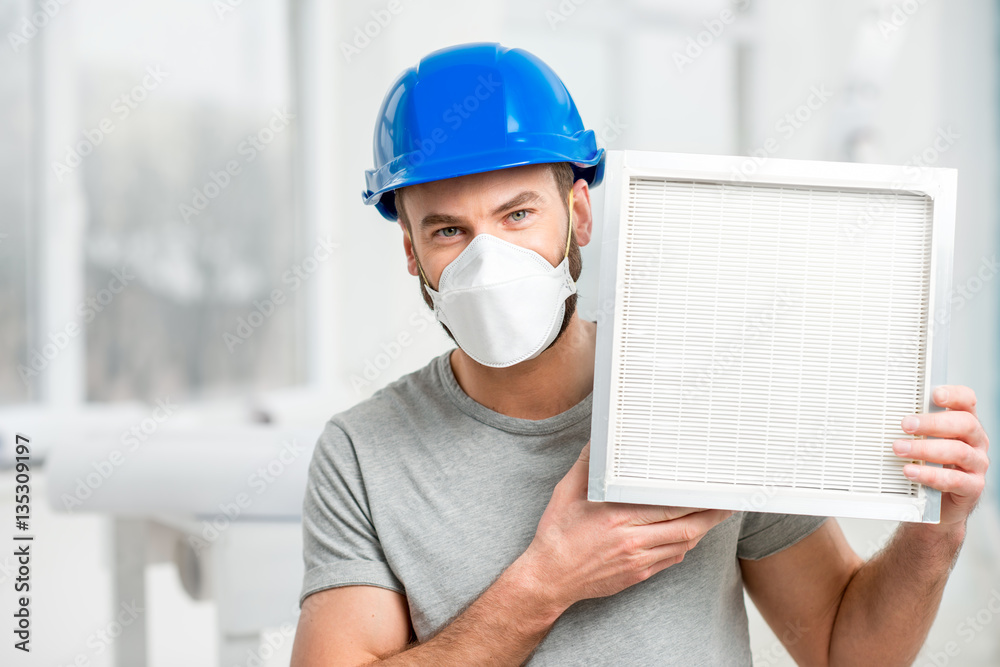 Worker holding air filter for installing in the house ventilation system. Purity of the air concept