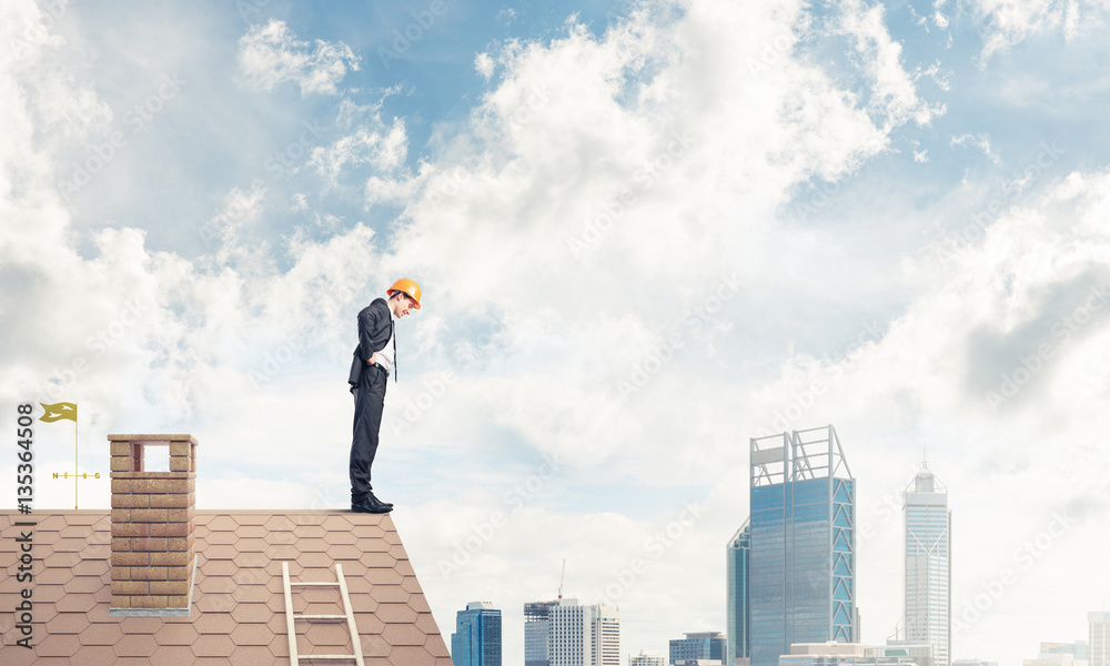 Businessman looking down from roof and modern cityscape at backg