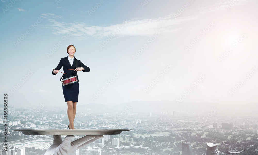 Attractive businesswoman on metal tray playing drums against cityscape background