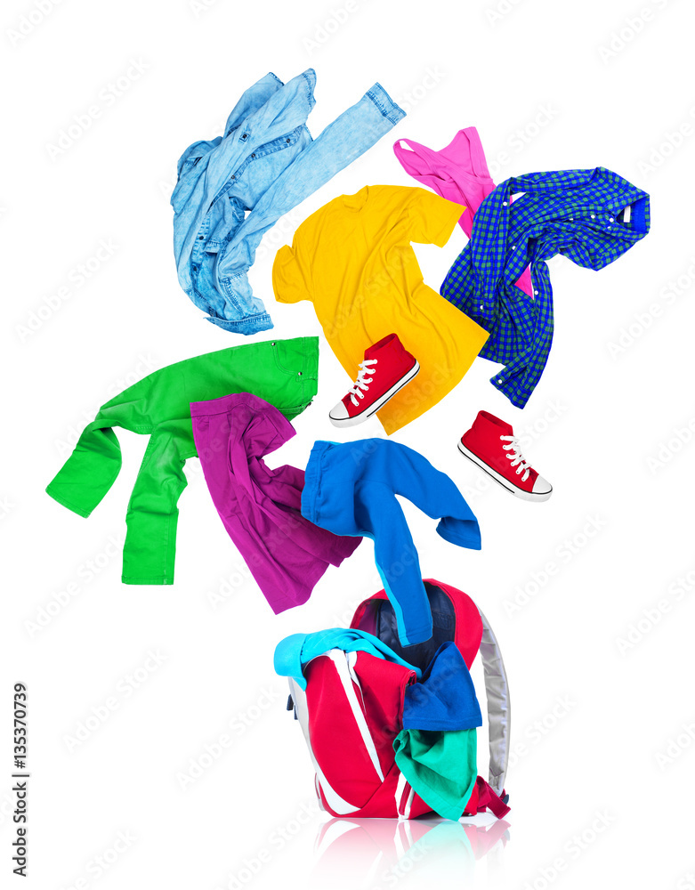 Colorful clothes are falling in a red backpack on a white backgr