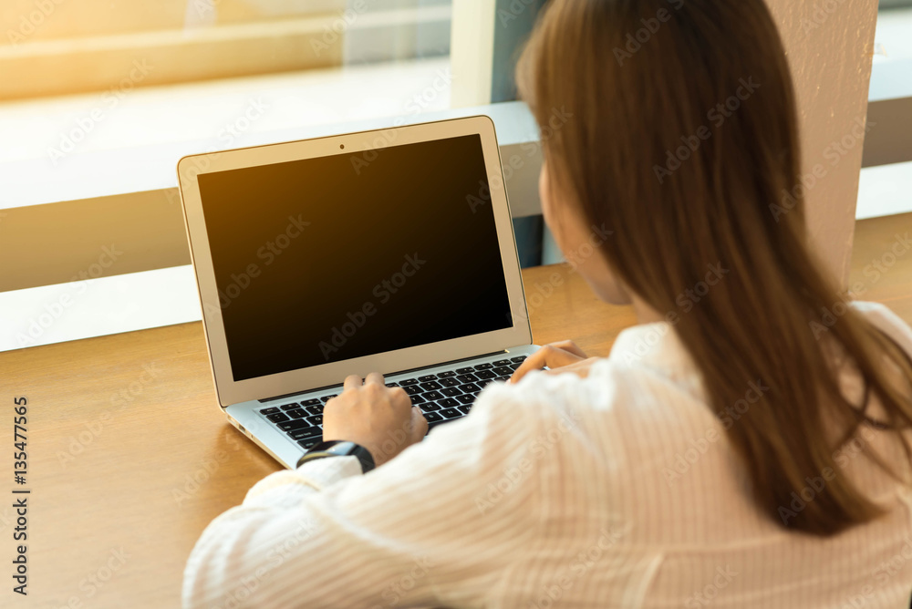 Woman use laptop with reflection on window glass