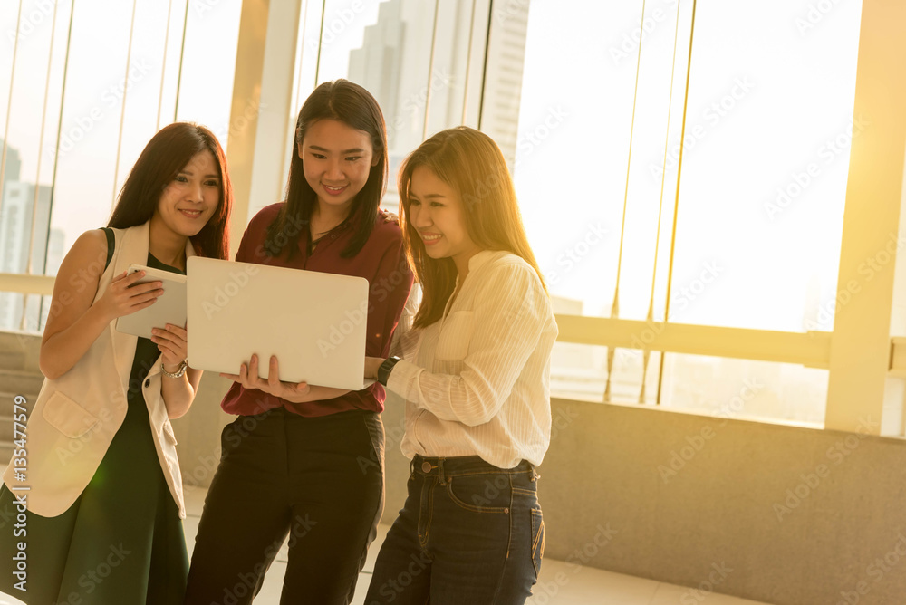 Three woman use laptop together in afternoon sun