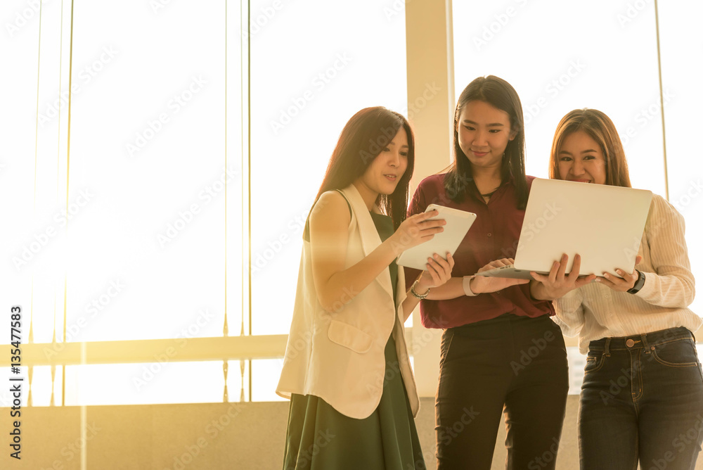 Three woman use laptop together in afternoon sun