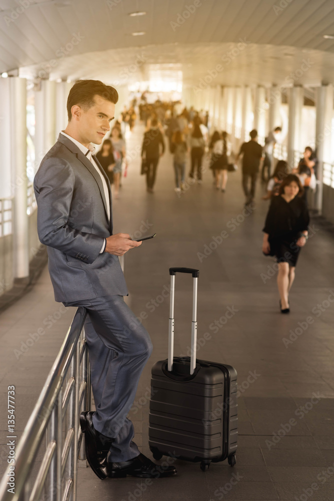 Business man with travel bag use smart phone on the walk way wit