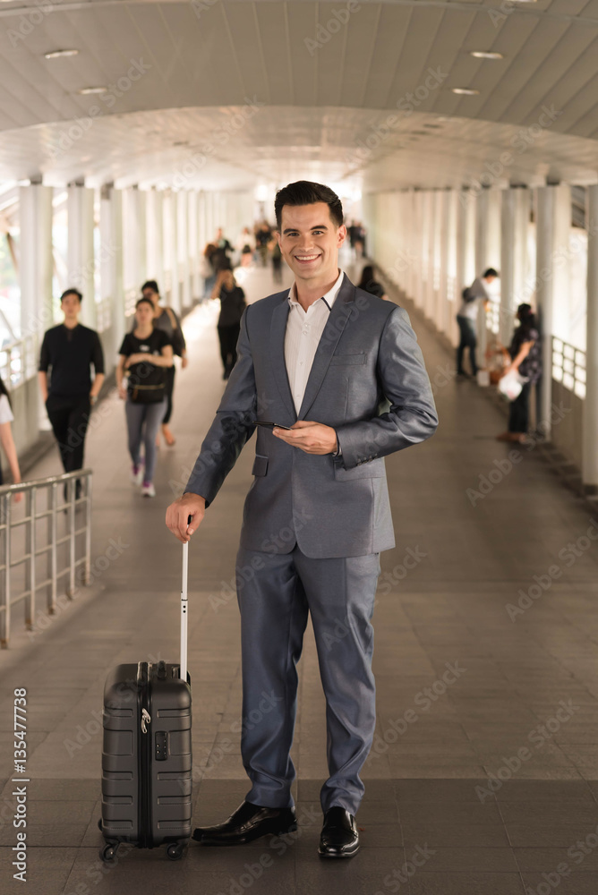 Business man with travel bag use smart phone on the walk way wit