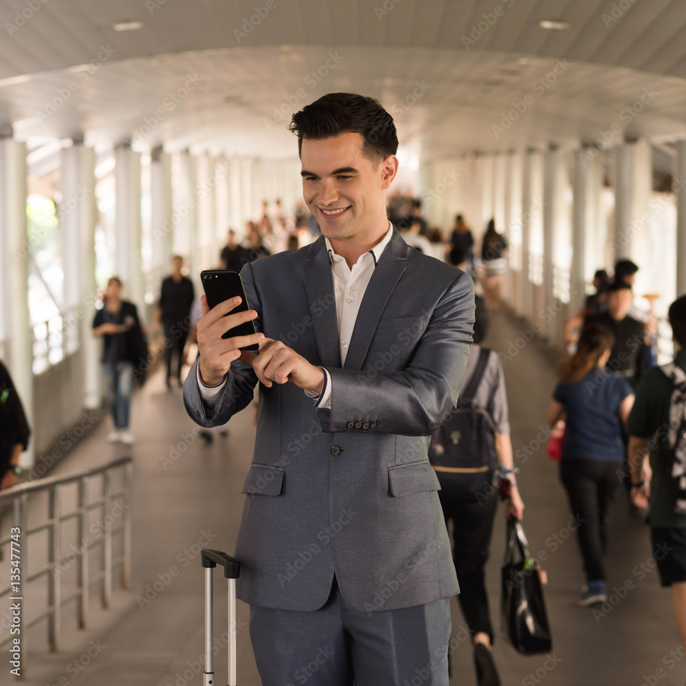 Business man with travel bag use smart phone on the walk way wit