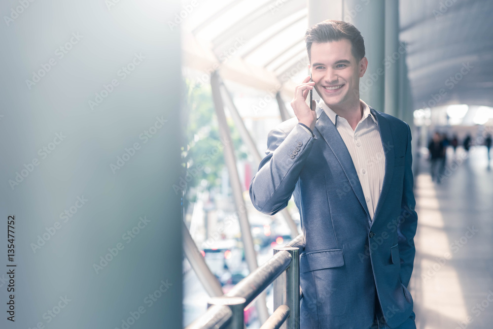 Business man with travel bag use smart phone on the walk way wit