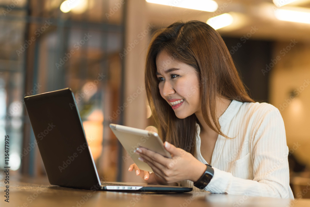 Woman holding tablet  while using laptop, freelance or nadmad wo