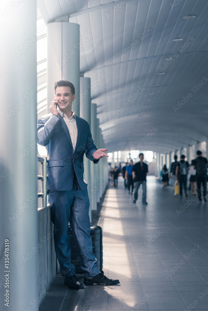 Business man with travel bag use smart phone on the walk way wit