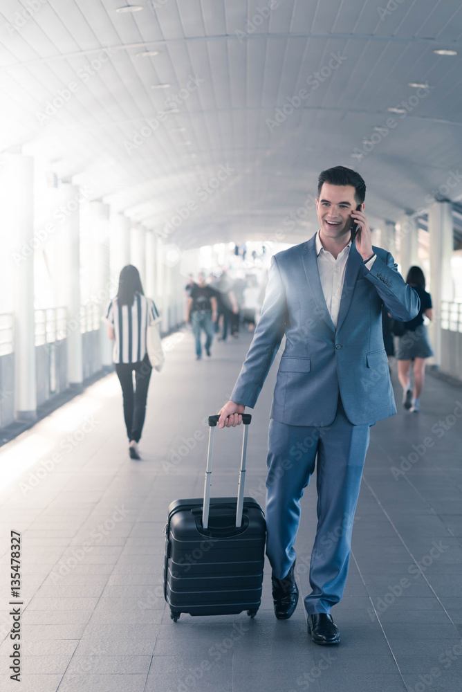 Business man with travel bag use smart phone on the walk way wit