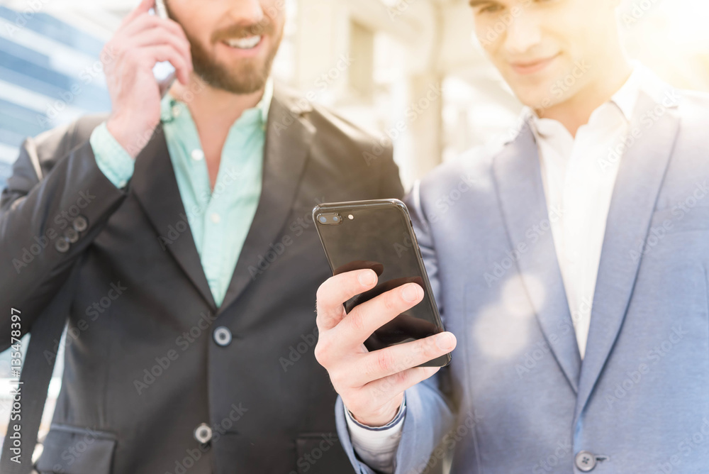 Two Westerner Business men talk and use smart phone