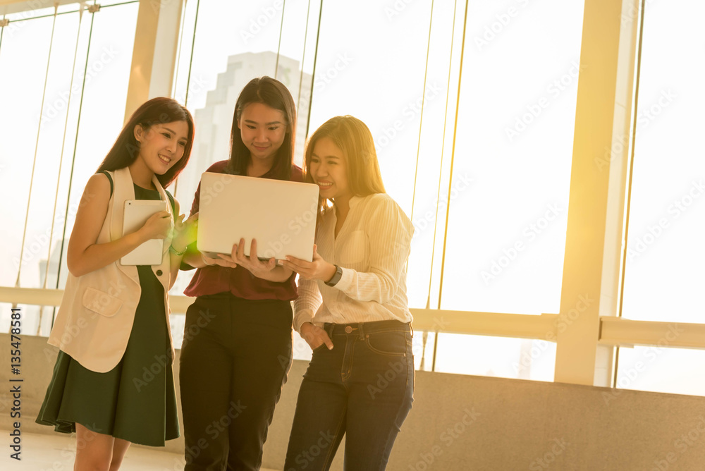 Three woman use laptop together in afternoon sun