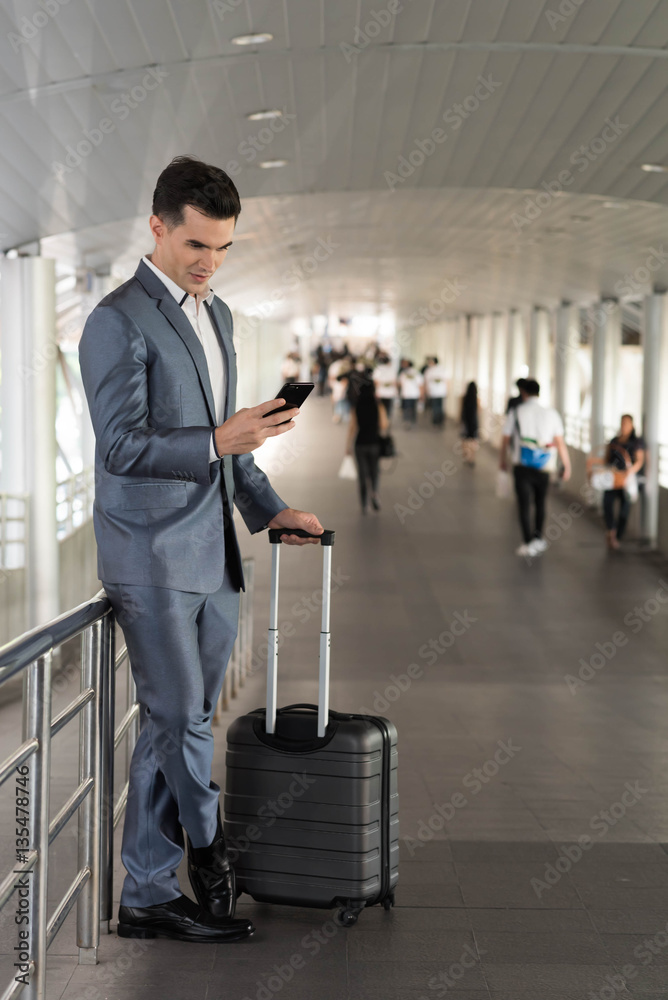 Business man traveling use smart phone on the walk way with crow